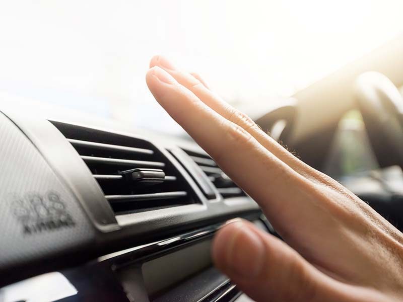 Person testing car air conditioner by having hand over it